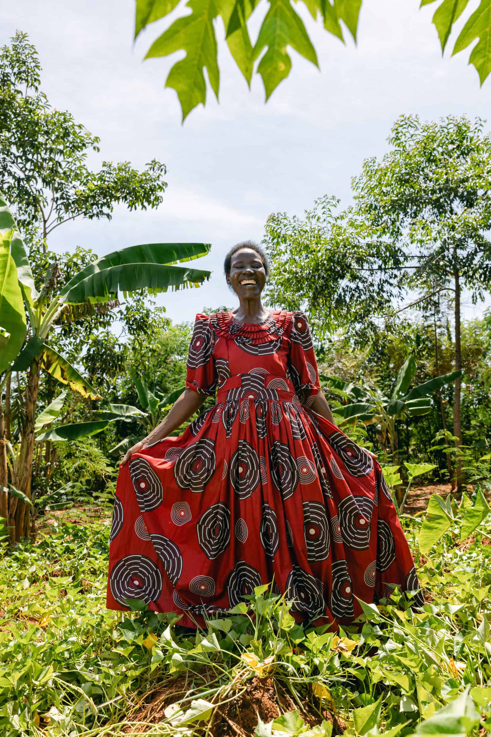 Justine in her vibrant red dress standing in her Forest Garden.