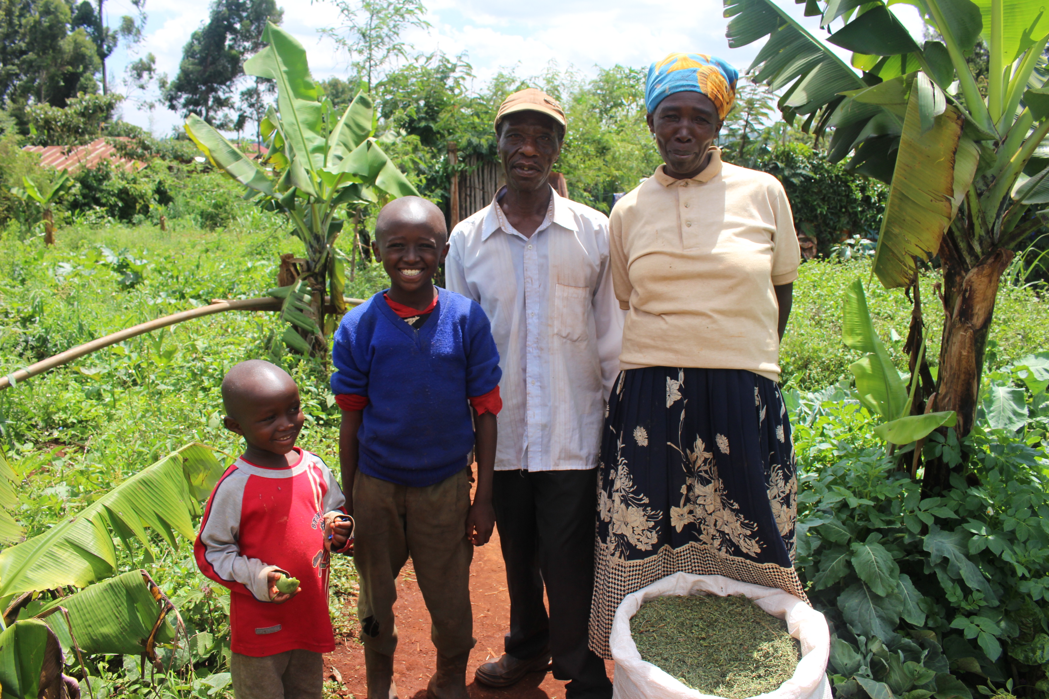 Peter Kamumu with his family with dried fodder tree leaves in a sack
