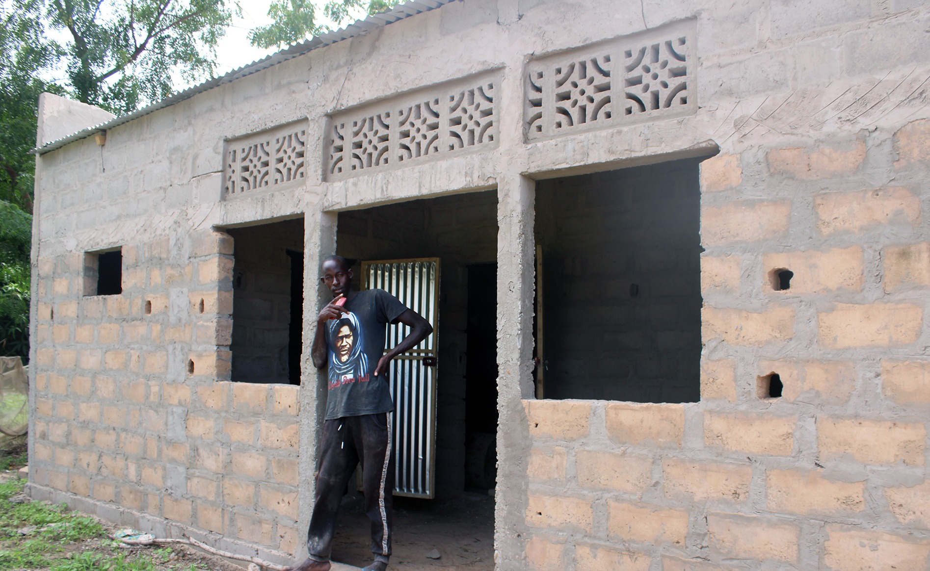 Mor Niang stands proudly by his newly constructed home, made possible through the income from his thriving Forest Garden in Senegal.